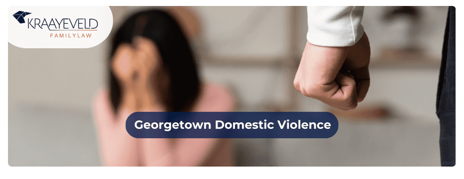 Close-up of the clenched fist of a man and a crying woman sitting behind suggesting domestic violence